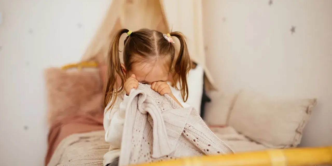 Kleines Kind mit Zöpfen versteckt sich unter einer Decke, weil es Angst vor Monstern hat.