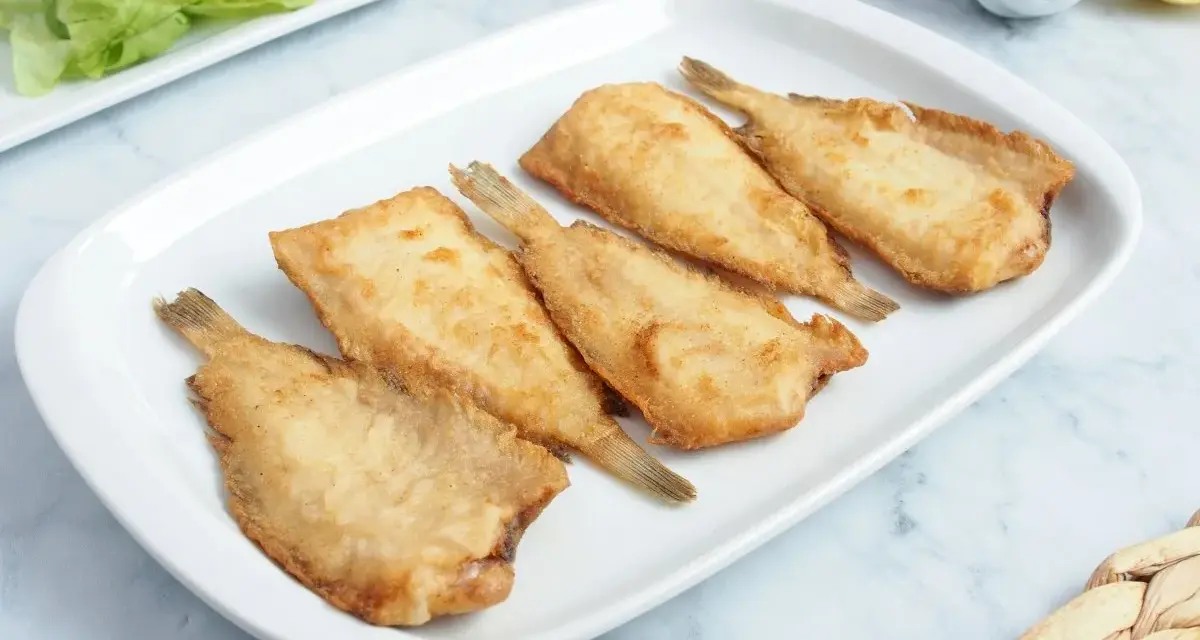 Cinco acedias fritas doradas y crujientes en una bandeja blanca, listas para disfrutar.