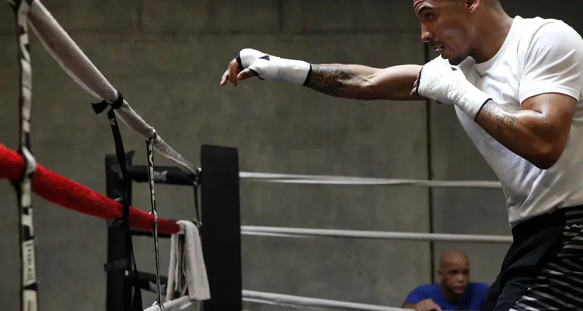 Un boxeur s'entraîne en shadow boxing dans un ring, concentré sur ses mouvements.