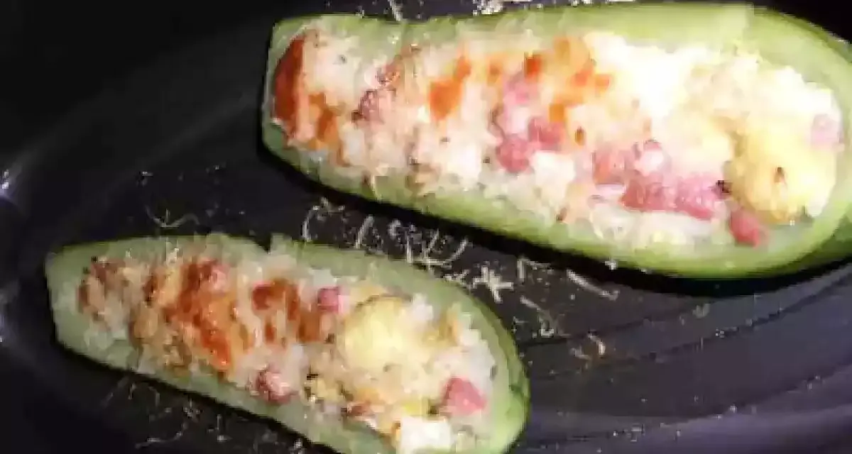 Zucchine ripiene di riso, condite con pomodoro e formaggio, pronte per essere gustate.