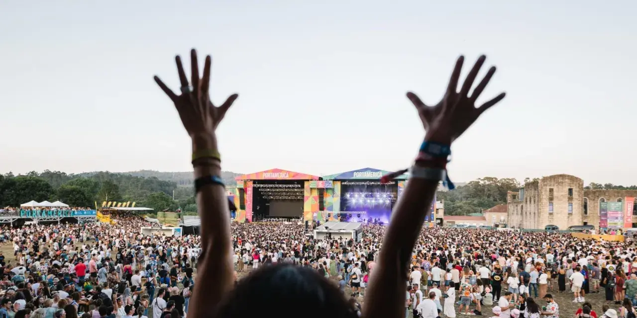 Manos alzadas en el festival Portamérica, disfrutando de la música y la multitud bajo un cielo despejado.