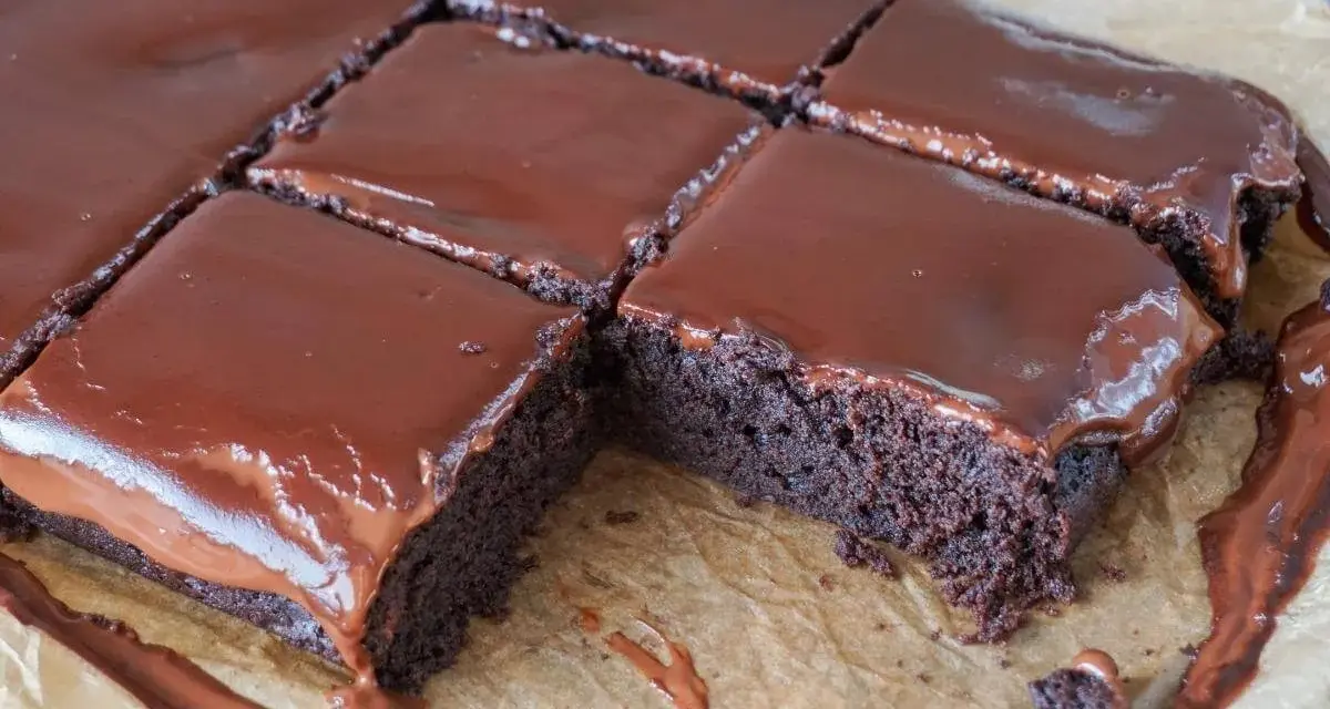 Saftige, vegane Brownies mit glänzendem Schokoladenguss, in Quadrate geschnitten. Ein Genuss für alle Schokoladenfans!