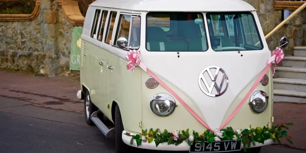 Klasyczny VW Transporter, ozdobiony różową wstążką i kwiatami, gotowy do transportu gości. Zasady dopisywania informacji o noclegu i transporcie dla gości są jasne.
