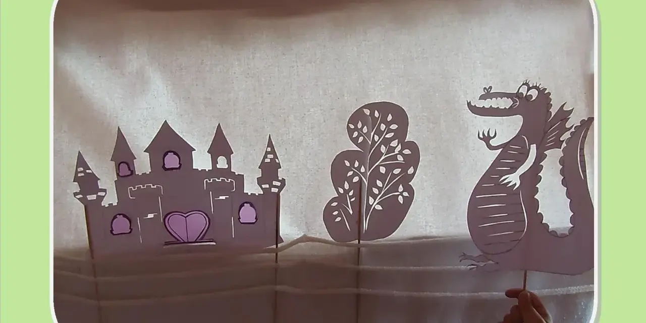 Théâtre d'ombres : château, arbre et dragon en papier, manipulés par une main.