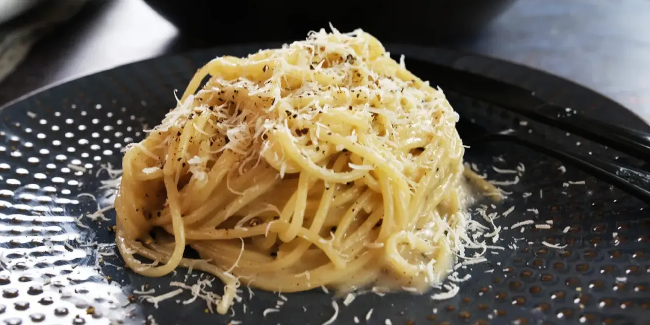 Pyszne spaghetti Cacio e Pepe, posypane startym parmezanem i świeżo mielonym pieprzem. Idealne na szybki obiad.