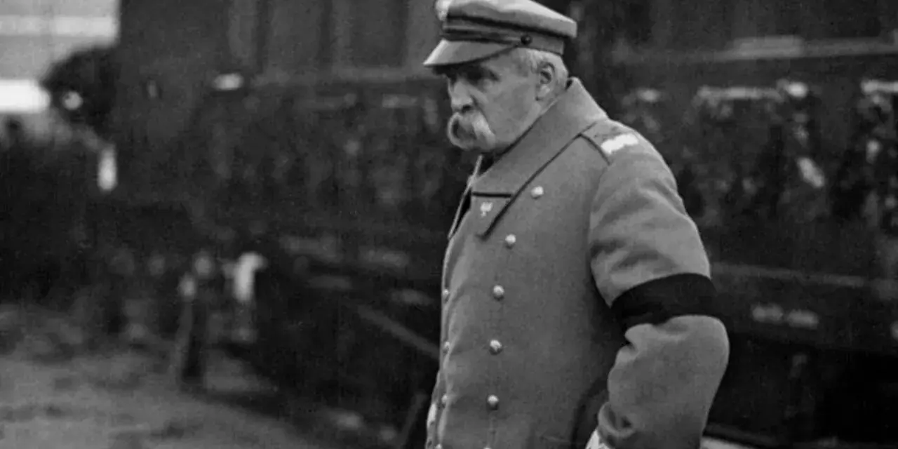 Marszałek Józef Piłsudski w mundurze, z czarną opaską na ramieniu, symbolizującą żałobę. W tle widać tłum ludzi, być może podczas uroczystości pogrzebowych, gdy Józef Piłsudski jak zmarł.