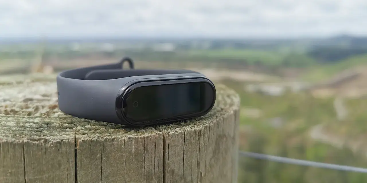 Czarny Mi Band 4 na drewnianym słupku, idealny do śledzenia aktywności. To najlepsza aplikacja do Mi Band 4 dla aktywnych osób.