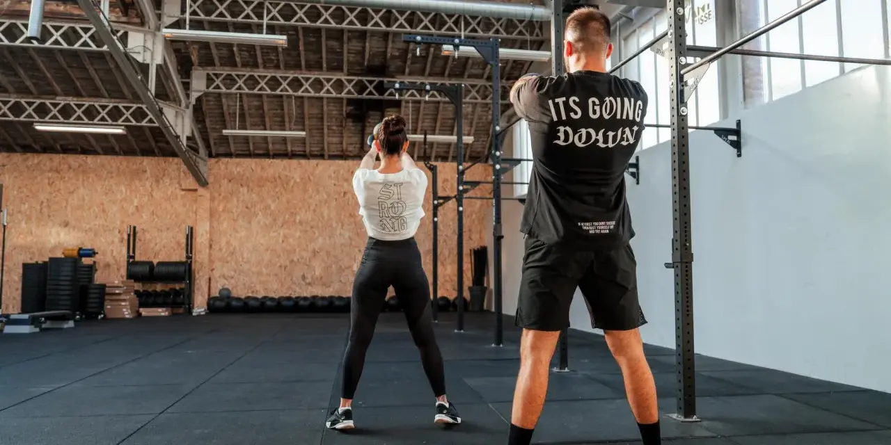 Para ćwicząca z kettlebell w siłowni CrossFit.