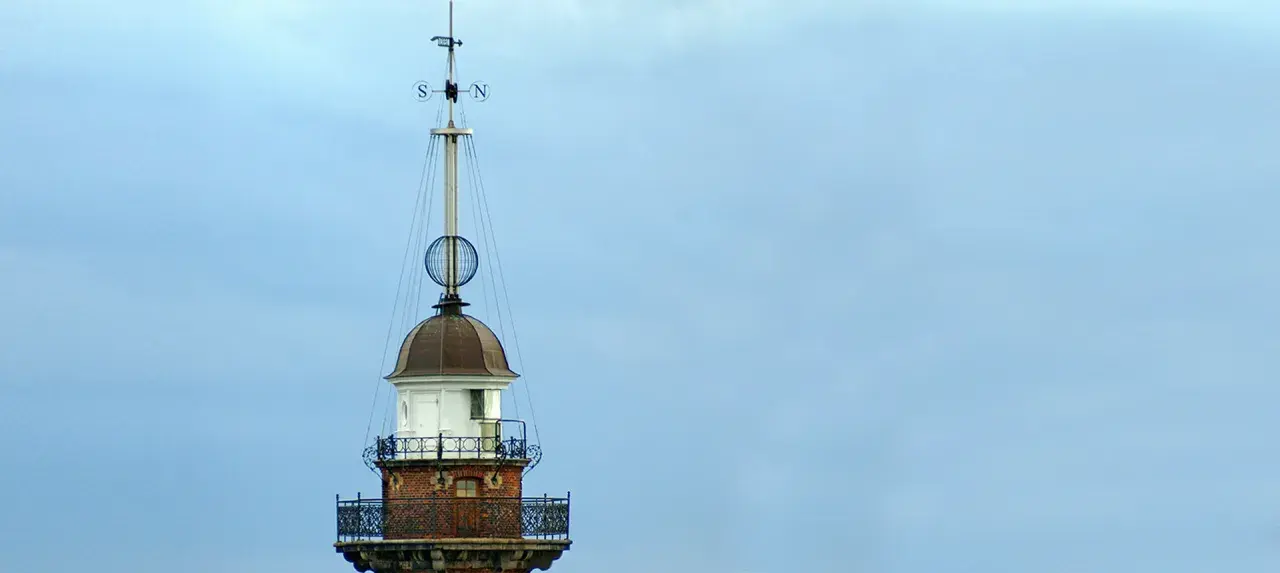 Szczyt latarni morskiej w Gdańsku z wiatrowskazem i kulistą ozdobą.
