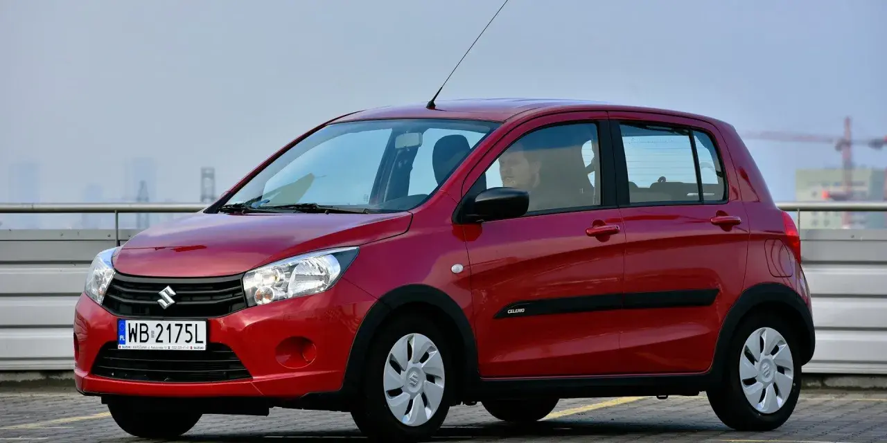 Czerwony Suzuki Celerio z polskimi tablicami rejestracyjnymi WB 2175L zaparkowany na zewnątrz.