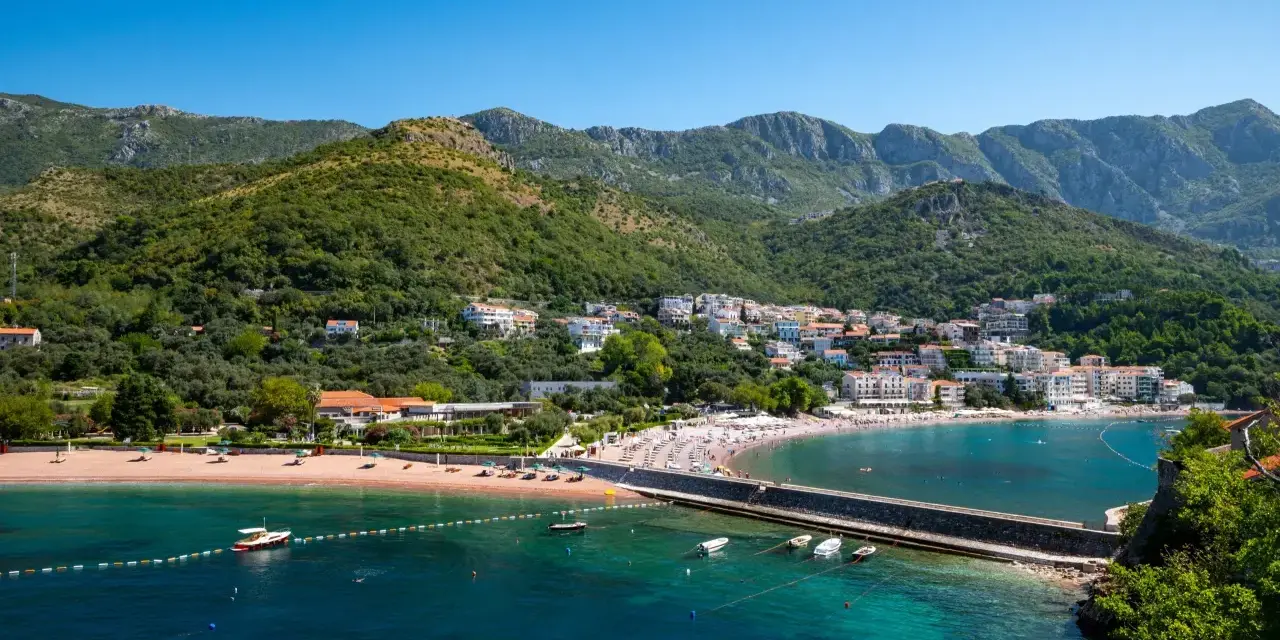 Malownicza zatoka w Czarnogórze, z piaszczystą plażą, turkusową wodą i górami w tle. Idealne miejsce na kempingi i wakacje.