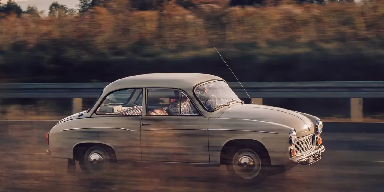 Klasyczny Syrena 105 na drodze, uchwycony w dynamicznym ujęciu panning shot.