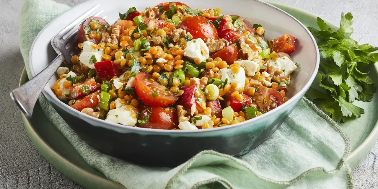 Ein bunter rote Linsen Salat mit Tomaten, Mozzarella und Nüssen, appetitlich angerichtet.