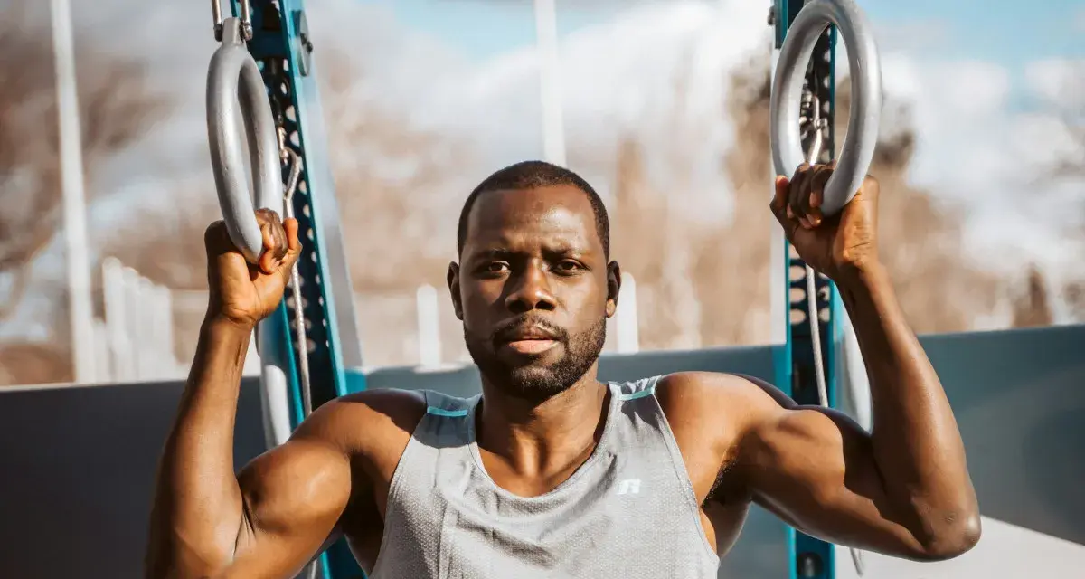 Un homme musclé s'entraîne avec des anneaux de street workout maison.