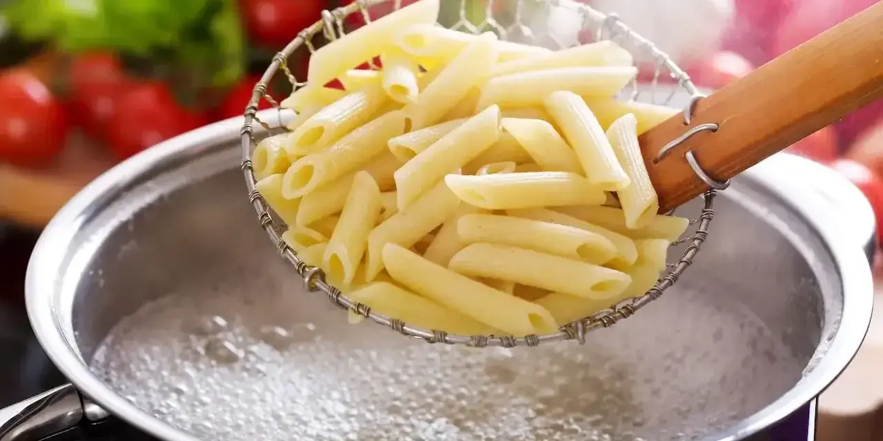 Penne makaron al dente, właśnie wyjęte z wrzątku, gotowe do sosu.
