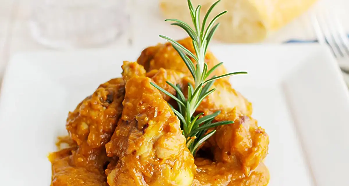 Sabroso pollo con almendras en una salsa dorada, adornado con romero fresco. Un plato que invita a disfrutar.