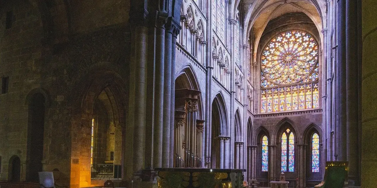 Wnętrze katedry z witrażami i ołtarzem. Miejsce sprzyjające refleksji nad teologią i duchowością.