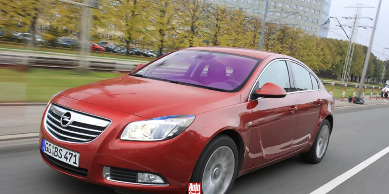 Czerwony Opel Insignia 1.6 Turbo w ruchu ulicznym. Wady tego modelu mogą dotyczyć np. spalania.