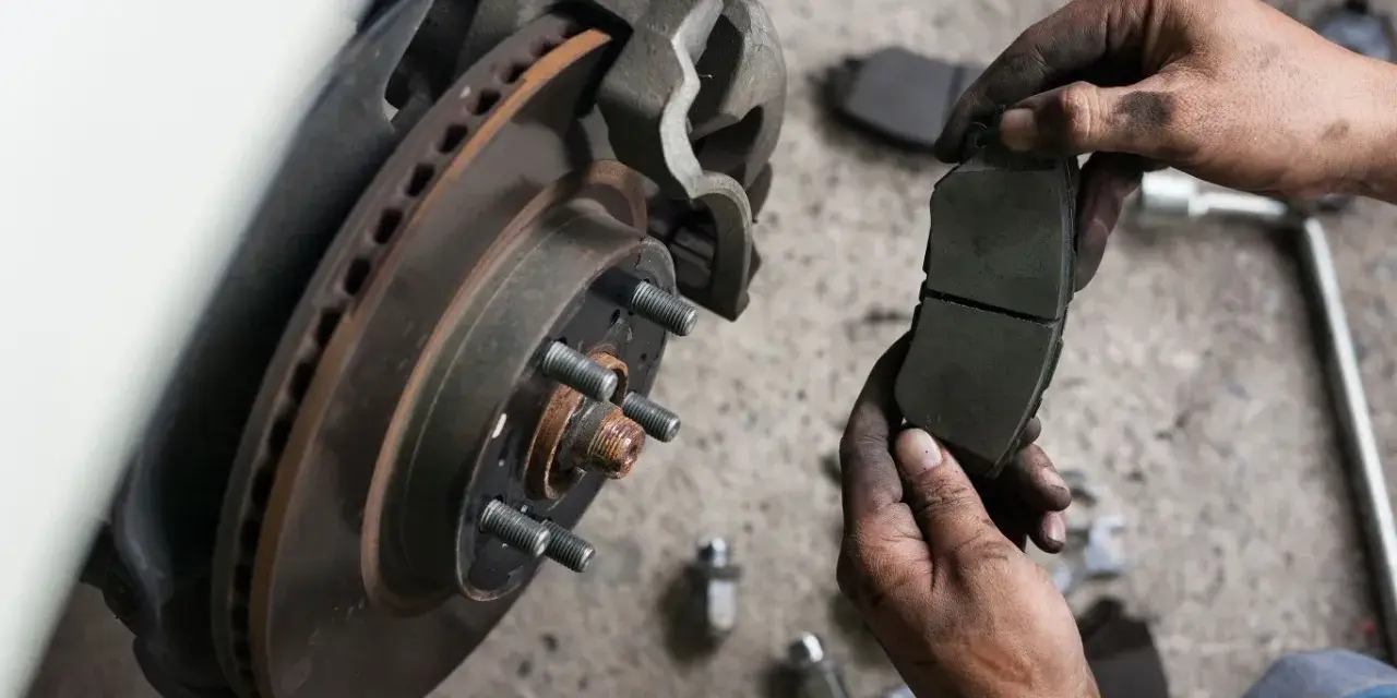 Mechanik trzyma nowe klocki hamulcowe. Sprawdź wymiana klocków hamulcowych cena i zadbaj o bezpieczeństwo.