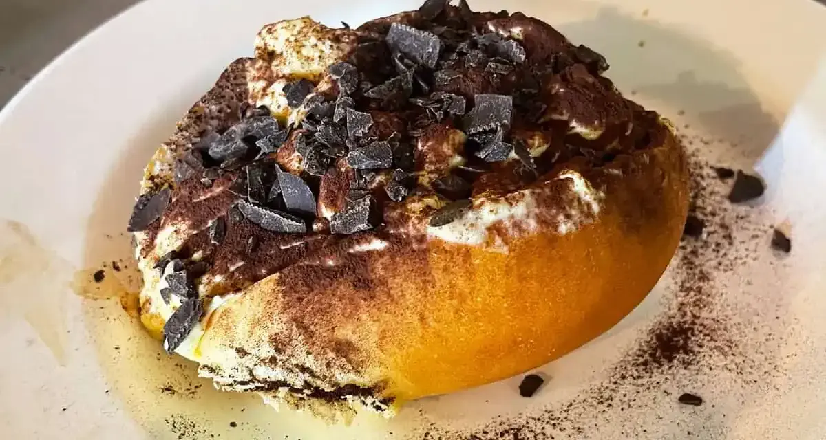Un dolce al cucchiaio, forse un tiramisù rivisitato, con cacao e scaglie di cioccolato. Un'idea golosa su cosa mangiare a Roma.
