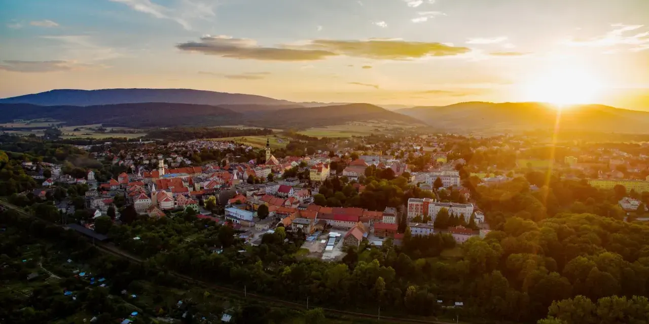 Zachód słońca nad Bystrzycą Kłodzką. Widok z lotu ptaka na miasto otoczone wzgórzami, idealna trasa na wieczorny spacer.