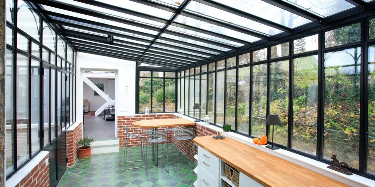 Un'idea per ampliare la cucina nella veranda: un ambiente luminoso con bancone in legno, zona pranzo e vista sul giardino.
