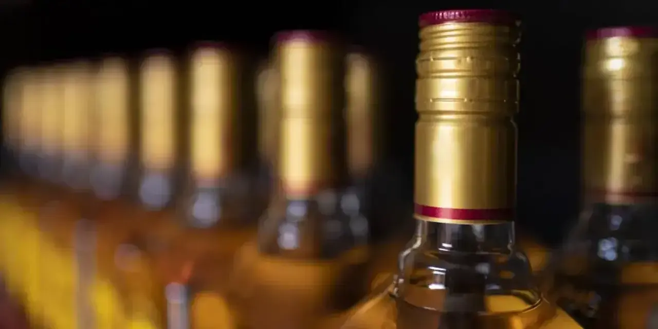 Rząd butelek z alkoholem, złote zakrętki. Zastanawiasz się, ile alkoholu można przewieźć samolotem Ryanair?