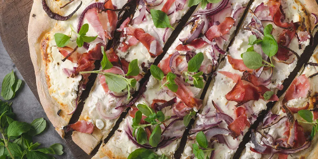 Flammkuchen mit Speck, roten Zwiebeln und frischen Kräutern – tolle Flammkuchen Belag Ideen für jeden Geschmack.