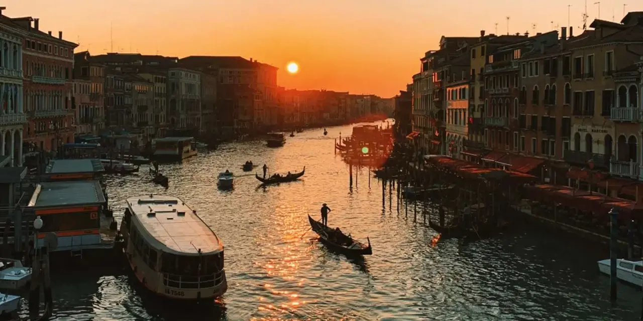 Tramonto sul Canal Grande, con gondole e vaporetti. Un'immagine da uno dei tanti punti panoramici di Venezia, con il sole che illumina l'acqua.
