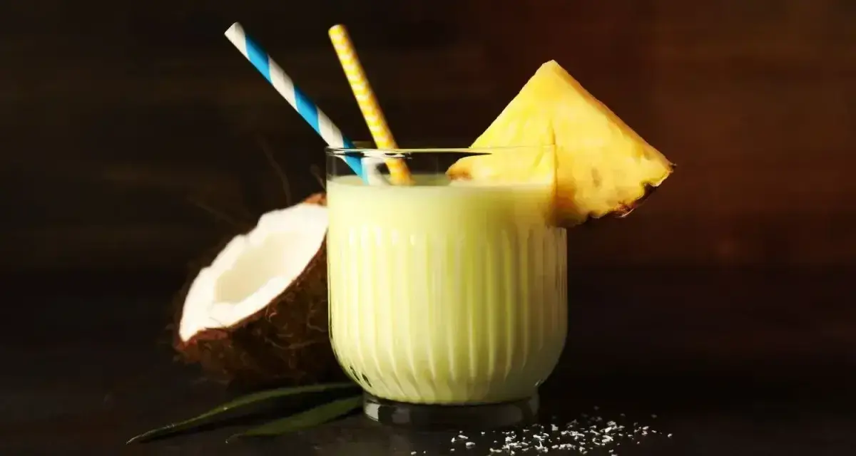 Orzeźwiający drink z mlekiem skondensowanym, ananasem i kokosem, ozdobiony słomkami. Idealny na tropikalne popołudnie.