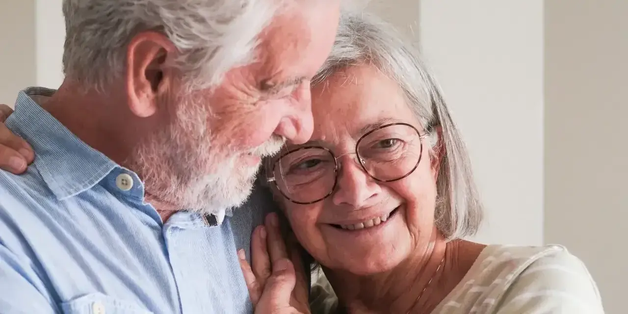 Uśmiechnięta para seniorów, która cieszy się życiem i przywilejami po 75 roku życia. Ich miłość kwitnie.