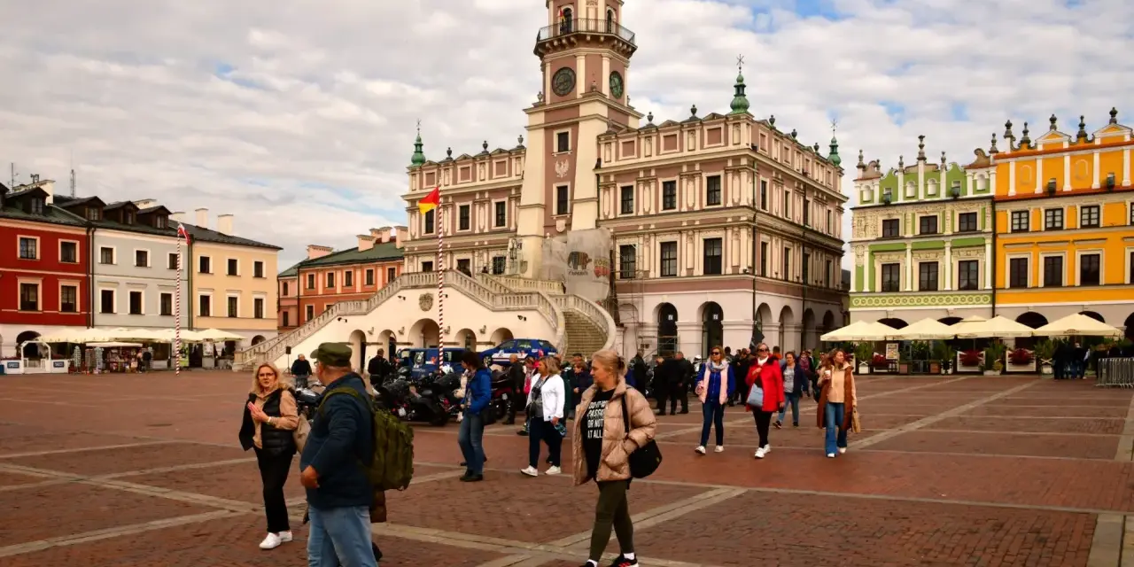 Rynek w Zamościu, idealne miejsce na wycieczki objazdowe z Lublina. Kolorowe kamienice i ratusz tworzą malowniczą scenerię dla spacerujących turystów.
