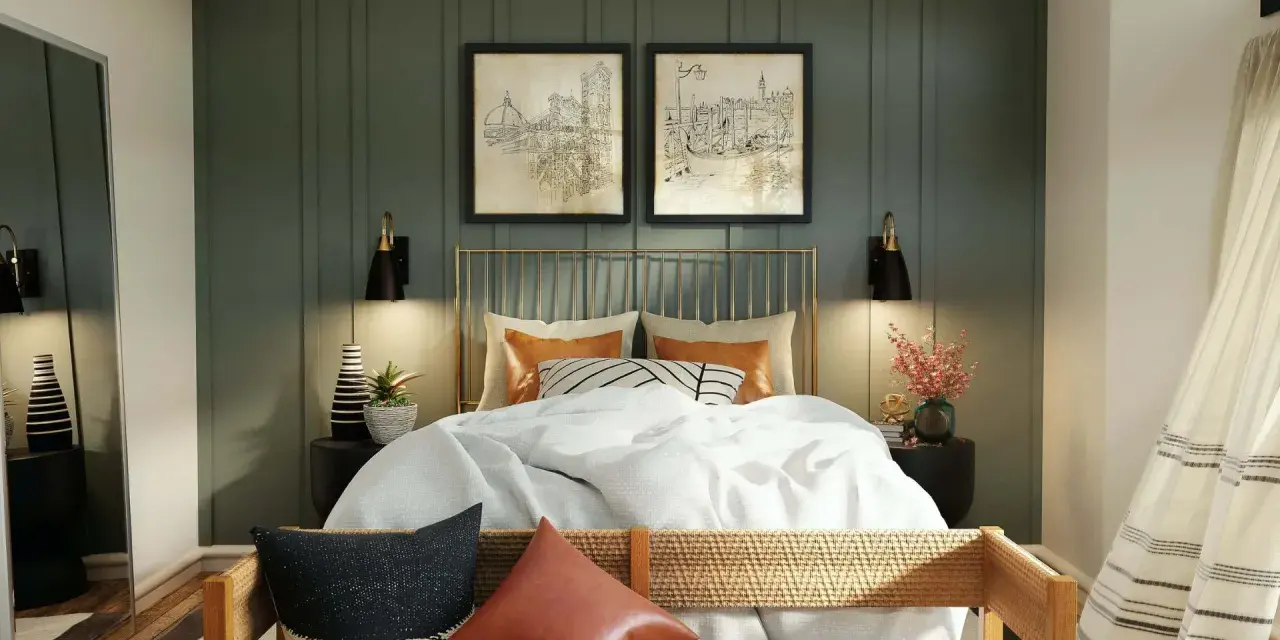 Elegantes dormitorios pequeños con encanto. Cama dorada con ropa blanca, dos cuadros de ciudades y lámparas negras.