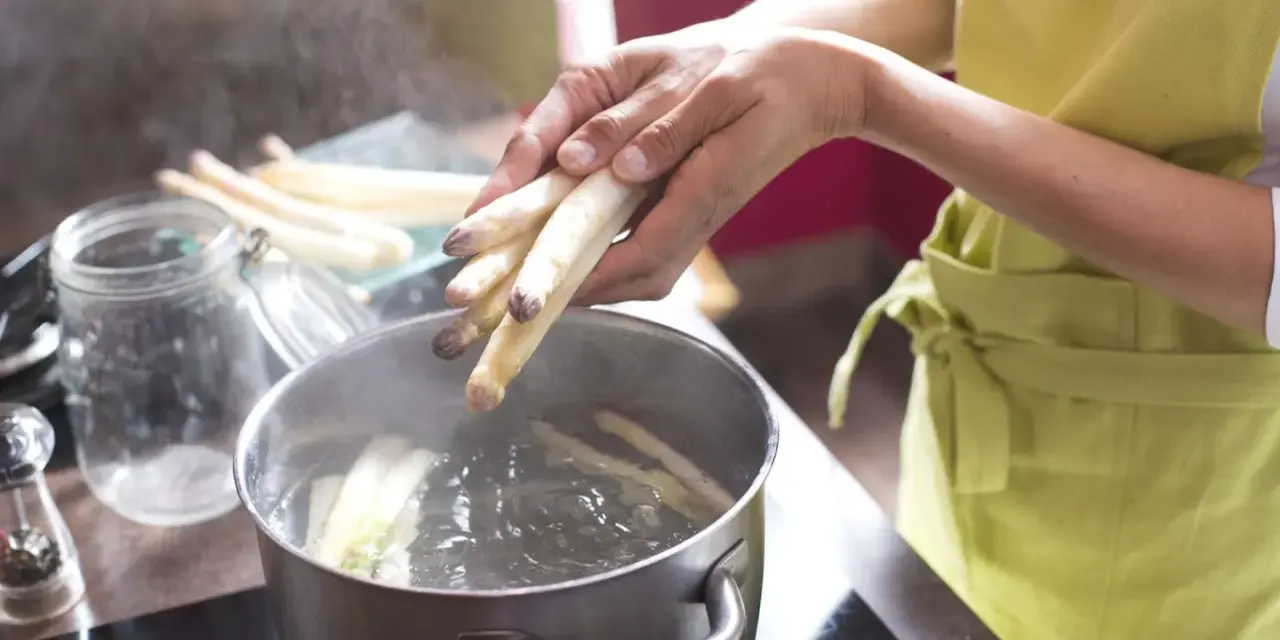 Frischer weißer Spargel wird in kochendes Wasser gegeben. Die Frage, wie lange muss Spargel kochen, beschäftigt viele Hobbyköche.