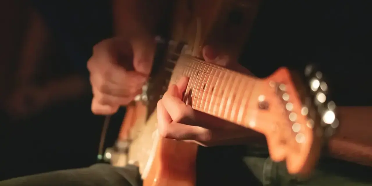 Ręce grające na gitarze elektrycznej, idealne do nauki jak nauczyć się grać na gitarze elektrycznej.