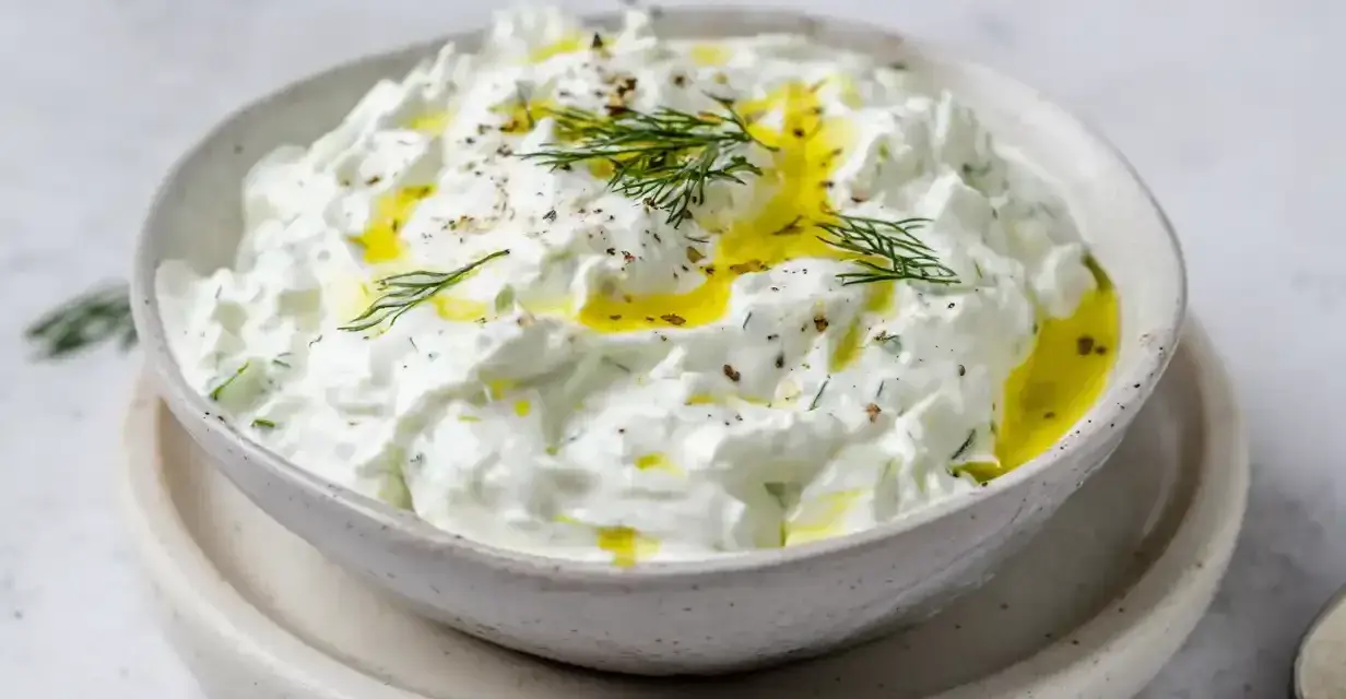 En skål med krämig tzatziki, perfekt för ditt tzatziki recept. Toppad med olivolja och färsk dill.