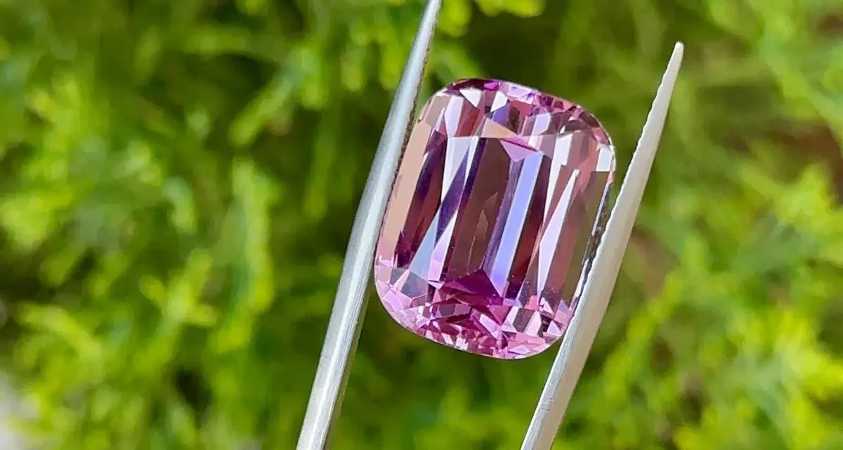Una splendida kunzite rosa tenuta da una pinzetta, che ne esalta le proprietà e la brillantezza.