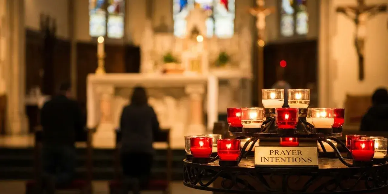 Candles glow in a church, with a sign reading "Prayer Intentions." People kneel in prayer, their mass intentions illuminated by the soft light.