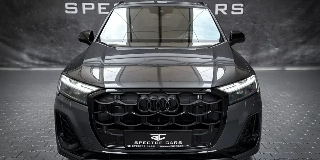 Przód ciemnoszarego Audi Q7 z czarnym grillem i światłami LED.