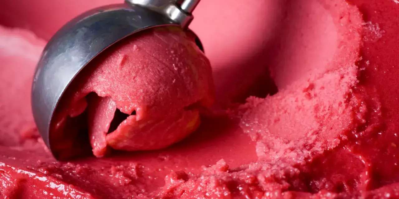 Cremiges Erdbeereis selber machen mit Eismaschine: Eine Kugel wird aus dem Behälter gehoben.