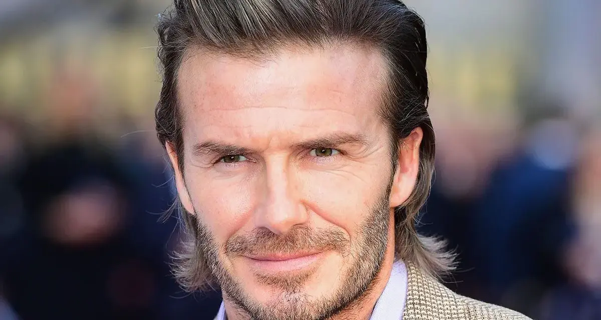 Hombre con pelo semi largo hombre liso, barba cuidada y traje a cuadros.
