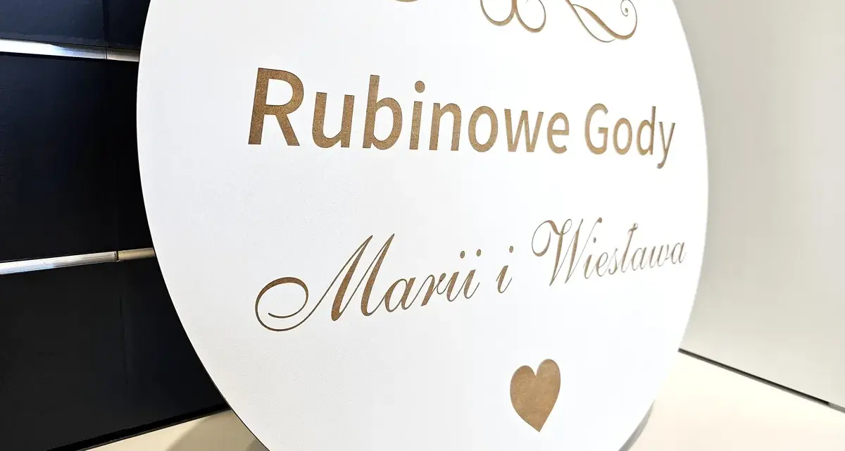 Okrągła tablica z napisem "Rubinowe Gody Marii i Wiesława" i cyfrą "40" upamiętnia 40 rocznicę ślubu.
