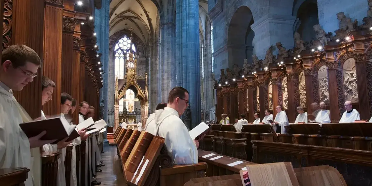 Men in white robes read from books in a grand cathedral, likely participating in matins, a morning prayer service.
