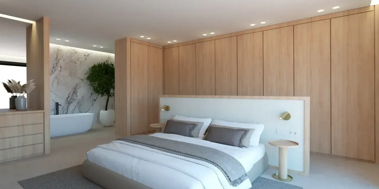 Elegante dormitorio con armarios de madera clara y detalles blancos. La cama, con ropa de cama blanca y cojines grises, se combina perfectamente con la pared de mármol y la bañera.