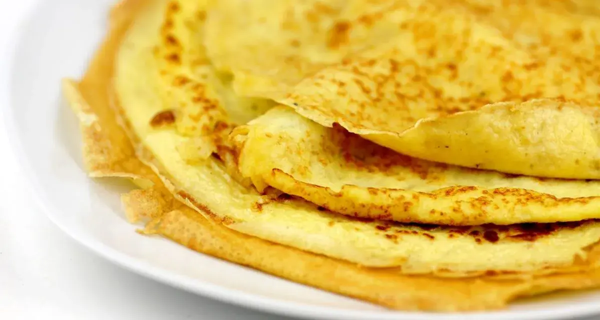 Ein Stapel goldbrauner Eierkuchen auf einem weißen Teller. Perfekt für ein schnelles und einfaches Eierkuchen Rezept.