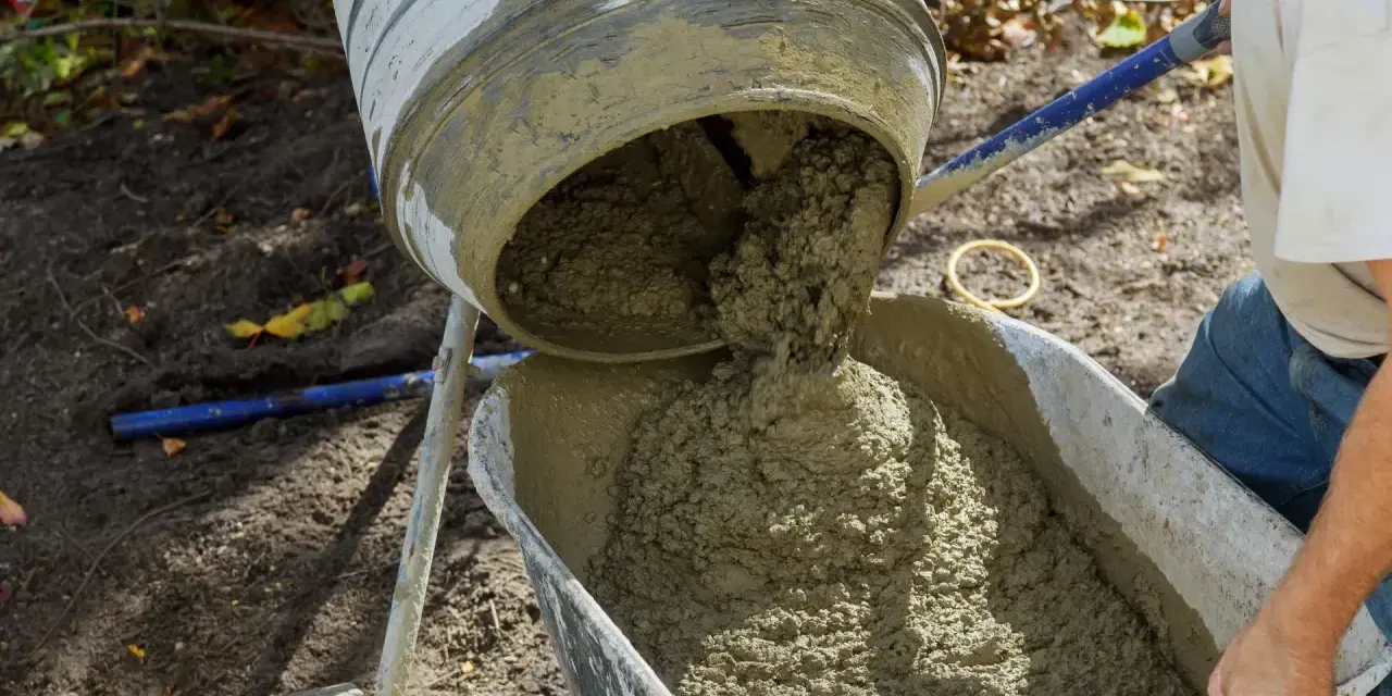 Betoniarka wylewa świeży beton do taczki. Oto jak zrobić beton w wiadrze, gdy potrzebujesz go do małych prac.