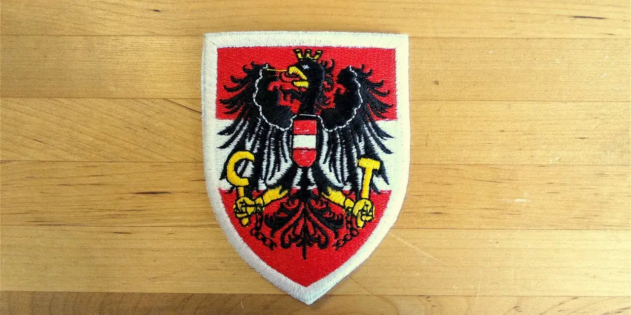 Naszywka z godłem Austrii: czarny orzeł z tarczą w biało-czerwone pasy, trzymający sierp i młot.