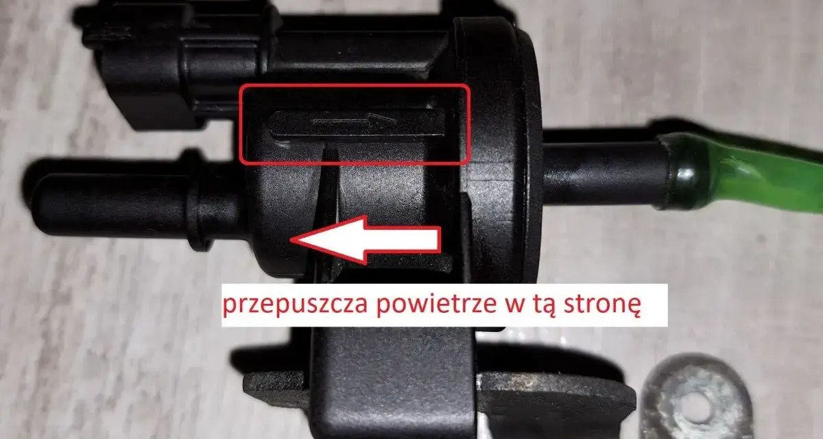 Zawór podciśnienia, potencjalna przyczyna błędu DTC P0170 w Volkswagen. Strzałka wskazuje kierunek przepływu powietrza.