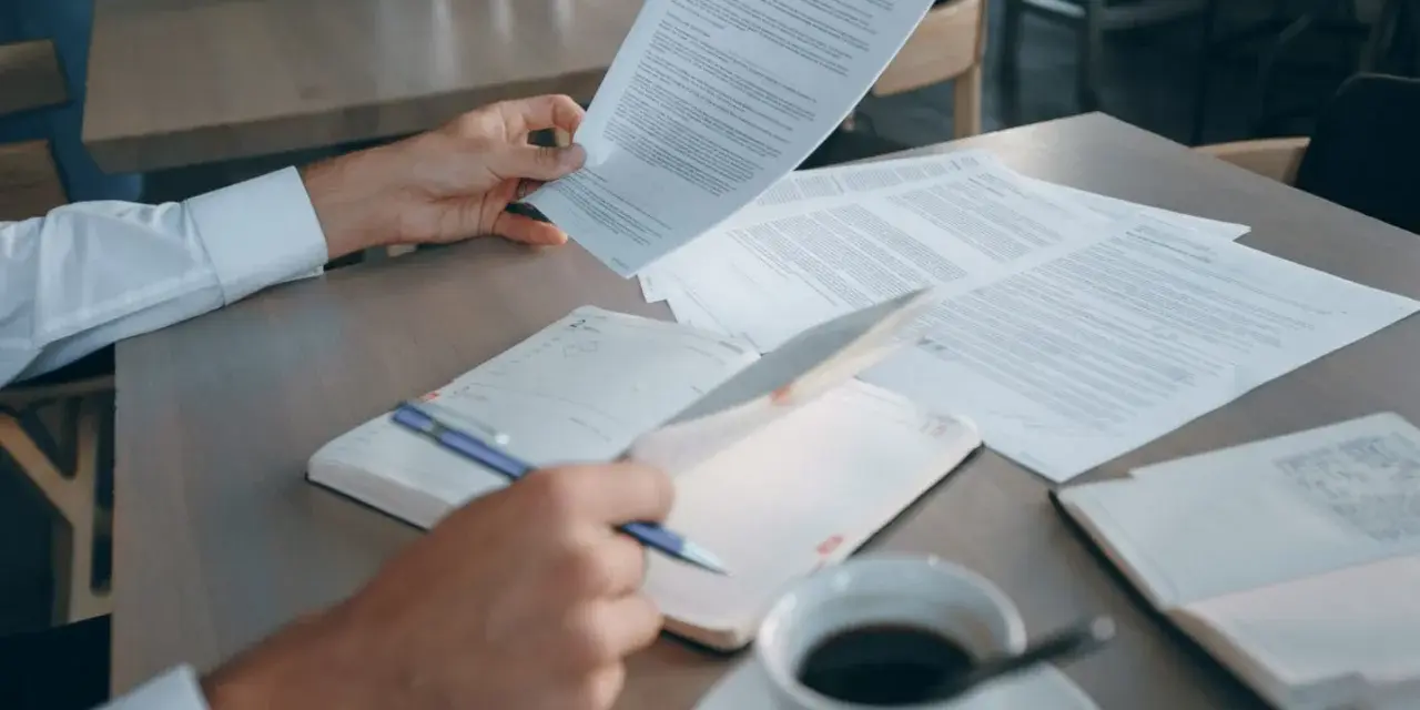 Mężczyzna analizuje dokumenty, szukając informacji o e-sądzie i nakazie zapłaty. Co dalej? Kawa i notatnik czekają.