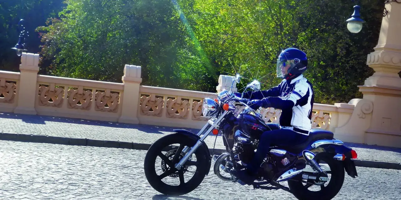 Motocyklista na Kymco Zing 125, zgrabnie pokonujący brukowaną ulicę. Dane techniczne tego modelu pozwalają na komfortową jazdę.